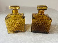 Two square amber glass decanters with diamond point pattern, front view showing sides and stoppers.
