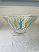 Side view of the clear glass chip bowl showing turquoise and green swirl design and flared shape.