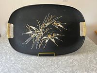 Full view of the rectangular black serving tray with bamboo wrapped handles and gold accented design on surface