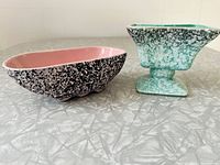 Two ceramic planters on a silver table: left is pink interior with black speckled exterior; right is green speckled pedestal style