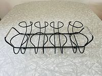 Top view showing the black metal wire frame beverage glass caddy with eight circular holders and white woven vinyl wrapped handles on each side.