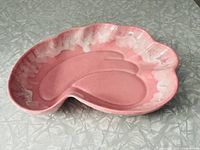 Front angled view of pink vintage ceramic display dish with white drip detailing around edges on grey textured surface.