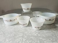 Photo showing all six Pyr-o-Rey bowls including two casseroles with handles and four custard cups arranged on a table.