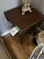 Top view of the antique drop leaf table with the leaves down, showing the wood surface and a decorative object on top.