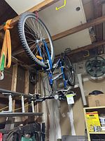 Blue American bicycle hanging inside garage, showing front and rear wheels, tires, and overall frame design.