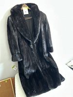 Full view of the dark brown fur jacket hanging on a hanger, showing overall length and collar.