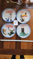 Set of 4 Guinness decorative collector plates with vintage beer advertising designs, placed on a wooden table next to a ruler for size reference.