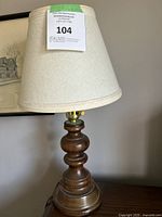 Full view of mid-century modern table lamp with cream fabric shade and wooden base.