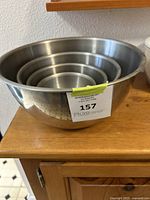 Four nested stainless steel mixing bowls sitting on a wooden surface.