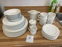 Full set of white Noritake porcelain including stacked bowls, dinner plates, cups, saucers, creamer, sugar bowl with lid and kettle.