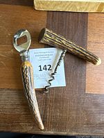 Pair of bar tools with stag antler-style handles on a wooden surface, includes bottle opener and corkscrew.