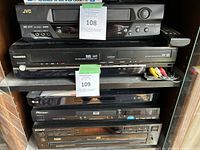 Front view of Toshiba combo unit with remote and AV cables inserted or placed nearby. Other electronics visible but not included in lot.