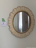 Oval vintage hanging mirror with cream pleated fabric frame and gold rope trim, clear reflective glass.