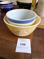 Two yellow Pyrex Shenandoah pattern mixing bowls (one large, one medium) and one smaller blue Pyrex Primary mixing bowl stacked together.
