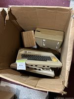 View of the cardboard box containing the Atari computer keyboard, external disk drive, and wooden box.