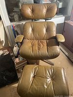 Front view of brown leather lounge chair and ottoman with metal bases