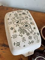 Rectangular ceramic casserole dish with green bird and floral design on cream background