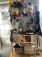 Photo of chrome IKEA kitchen stand loaded with various kitchen items including mixer, espresso machine, toaster oven, and other cookware to show storage capacity and design.