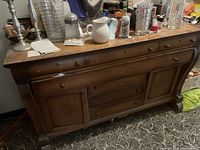 Full view of the large solid oak sideboard showing top surface, drawers, cabinet doors, and legs.