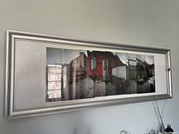 Silver-tone panoramic picture frame on wall containing a panoramic photo of a residential scene, showing glass intact and frame in good condition.