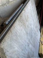 Three heavy slate pieces leaning against a wall, showing thickness and rough edges.