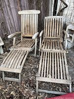 View of two teak wood loungers with natural weathered finish and slatted design including armrests and footrests