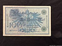 Obverse side of the 1908 German Empire 100 Mark banknote showing ornate blue-green patterns, German text, and serial number.