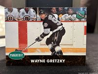 Front side photo of Wayne Gretzky hockey card showing him skating in black uniform with League Leader badge.