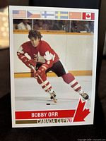 Front side of Bobby Orr hockey trading card from Canada Cup 1976, featuring player photo and tournament flags.