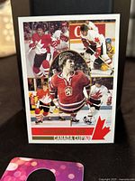 Front image of Bobby Orr Tournament MVP Canada Cup 1976 trading card with multiple hockey action photos and Canadian flag iconography.