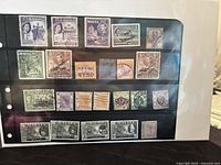 Photo of album page containing 22 vintage postage stamps from Malta, Malaya, and Hong Kong with various denominations and designs.