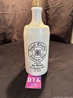 Full view of the vintage Hudson's Bay Royal Charter whiskey stoneware bottle on a black surface with visible cork stopper.