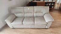 Front view of beige 3 seater leather sofa showing three seat and back cushions