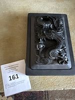 Top view of black slate ink box lid showing detailed Chinese dragon carving.