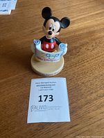 Front view of 1991 Mickey Mouse figure holding scroll with '1991 Walt Disney World' text on wooden base