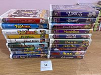Photo showing stacked VHS tapes with titles visible, includes Disney classics like 101 Dalmatians, Toy Story, The Jungle Book, Bambi, and others.
