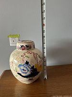Front and side view of the porcelain ginger canister with a measuring tape indicating about 7.5 inches tall.