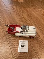 Photo of the Hallmark Kiddie Car Classics 1941 Junior Service Truck angled from the front left side showing the white cab and red cargo bed on wooden floor.