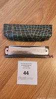 Hohner Chromonika II chromatic harmonica and green patterned hard case on wooden surface with auction card