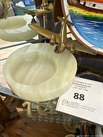 Marble or onyx ashtray with brass airplane figurine mounted on rim.