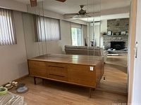Front view of teak sideboard against mirrored wall