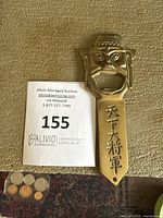 Front view of brass bottle opener showing warrior face and Asian characters