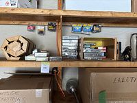 Shelf with wooden board and coiled wire, various small boxes of staples and screws sorted on the shelf