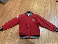 Front side of the red Disney varsity jacket with classic Mickey Mouse embroidery on chest and patches on sleeve and front pocket area.