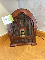 Front view of the vintage-style GE cathedral AM/FM radio showing wooden cabinet, speaker grille, tuning dial and control knobs.