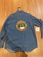 Back view of blue denim shirt showing large Pooh patch with text 'Pooh's 100 Acre State Park'