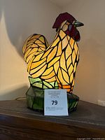 Full lit stained glass rooster lamp showing colored glass pieces on base and body.