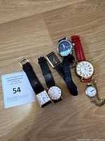 All six watches arranged side by side on wooden surface.