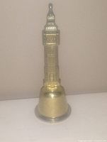 Image of a small metallic bell shaped like a vintage bell tower with detailed architecture, approximately 4 inches tall.