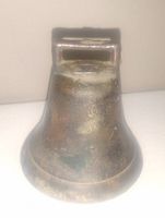Front and side view of antique bronze bell showing patina and rectangular top slot